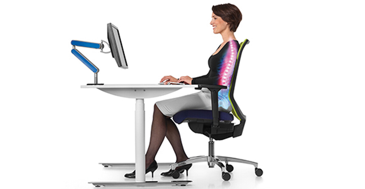 Lächelnde Frau arbeitet am Schreibtisch und sitzt in einem ergonomischen Stuhl von büroPARTNERteam Einrichtungs-GmbH