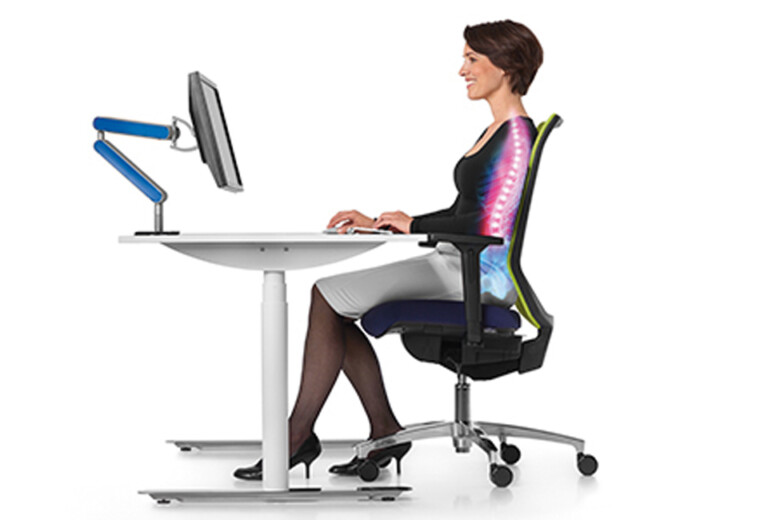 Lächelnde Frau arbeitet am Schreibtisch und sitzt in einem ergonomischen Stuhl von büroPARTNERteam Einrichtungs-GmbH