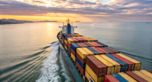 Ein Containerschiff fährt eine Küste entlang.