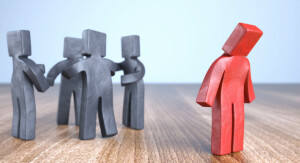 Eine Darstellung von fünf stilisierten Figuren, wobei vier davon miteinander interagieren und eine davon abseits steht und isoliert wirkt. Die isolierte Figur ist rot, während die anderen schwarz sind.