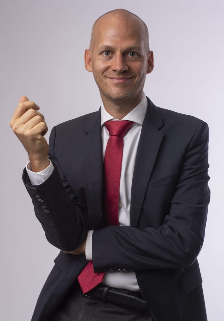 Porträt eines glatzköpfigen Mannes im dunklen Anzug.